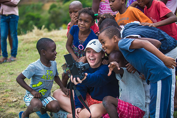 Female student surrounded by local school children