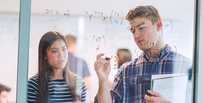 2 students writing on glass