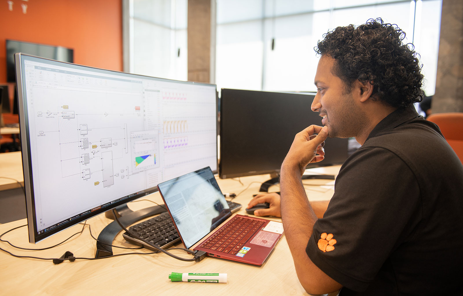 Graduate student smiling while looking over computer content on screen.