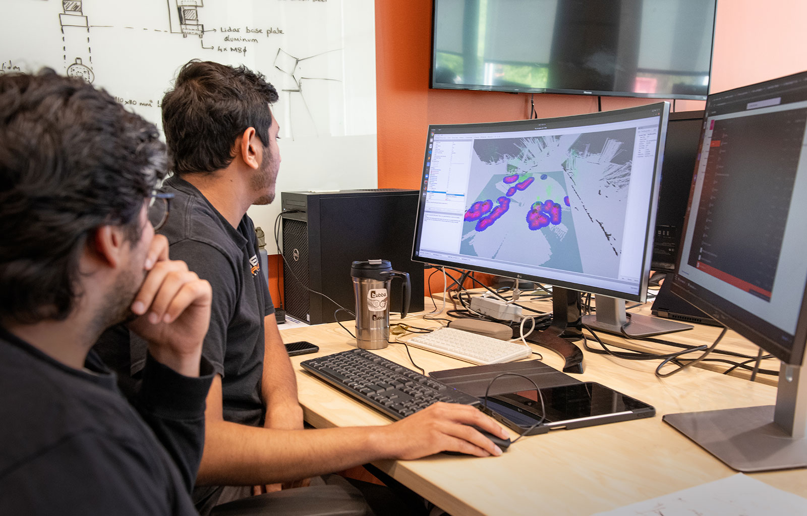 Two graduate students looking at data on monitor screen