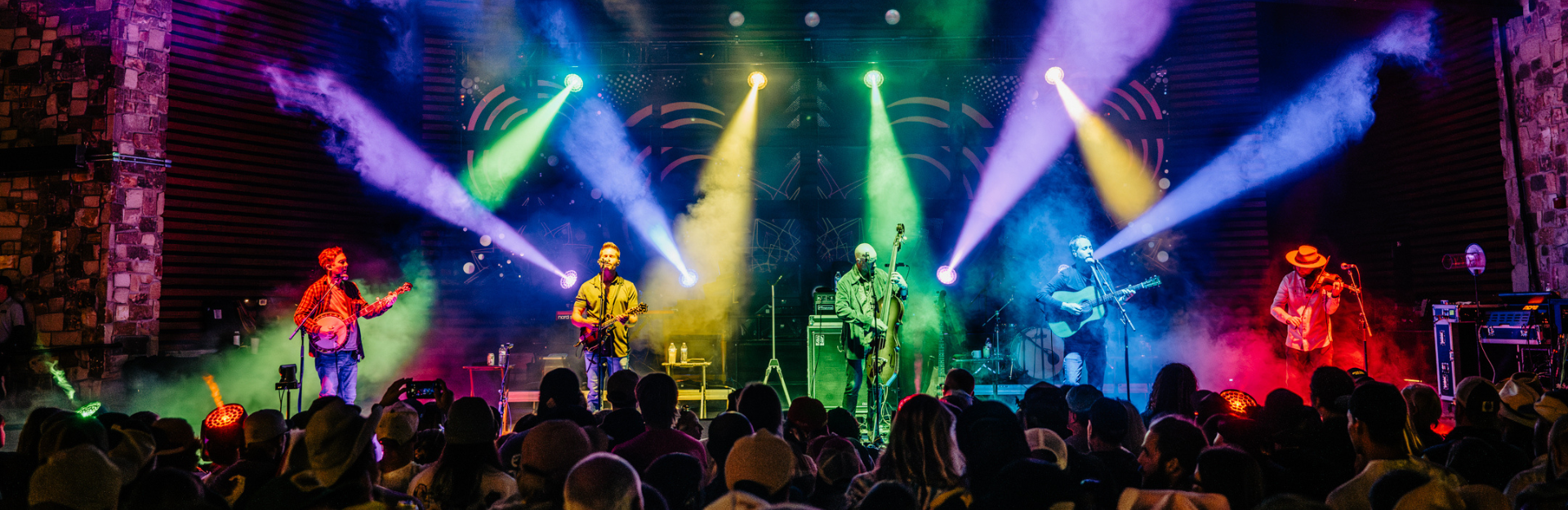 Live photo of the Yonder Mountain String Band performing onstage under colorful lights