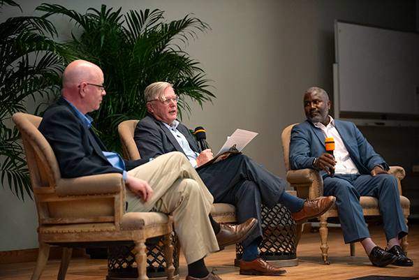 Three men sitting and speaking at event