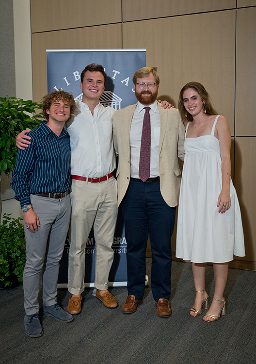 Three males and one female standing together for group photo.