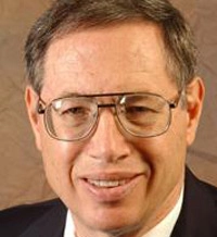 Professional headshot of a man with glasses, smiling against a neutral background.