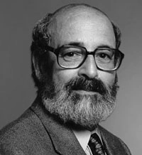 Black and white portrait of a bearded man wearing glasses and a suit.