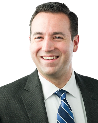 Professional headshot of a smiling man in a suit and tie.