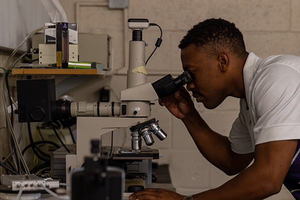 student looking into microscope