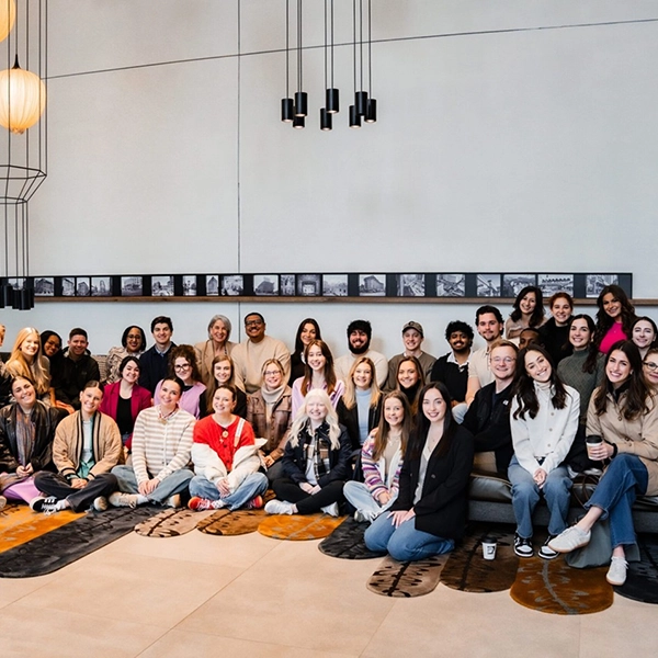 Group photo of a diverse team gathered in a modern space, smiling and posing together on a stylish rug.