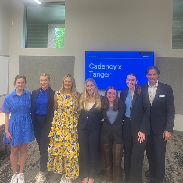 Group photo of the Cadency and Tanger teams, showcasing members in professional attire in a meeting room setting.