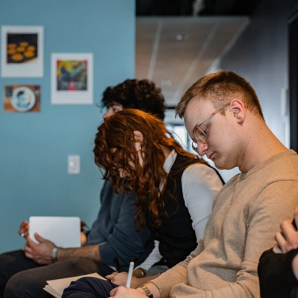 A group of individuals attentively taking notes during a meeting or discussion.