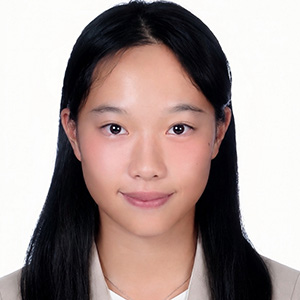 Studio-style headshot of a young woman with long straight dark hair, facing forward against a white background.