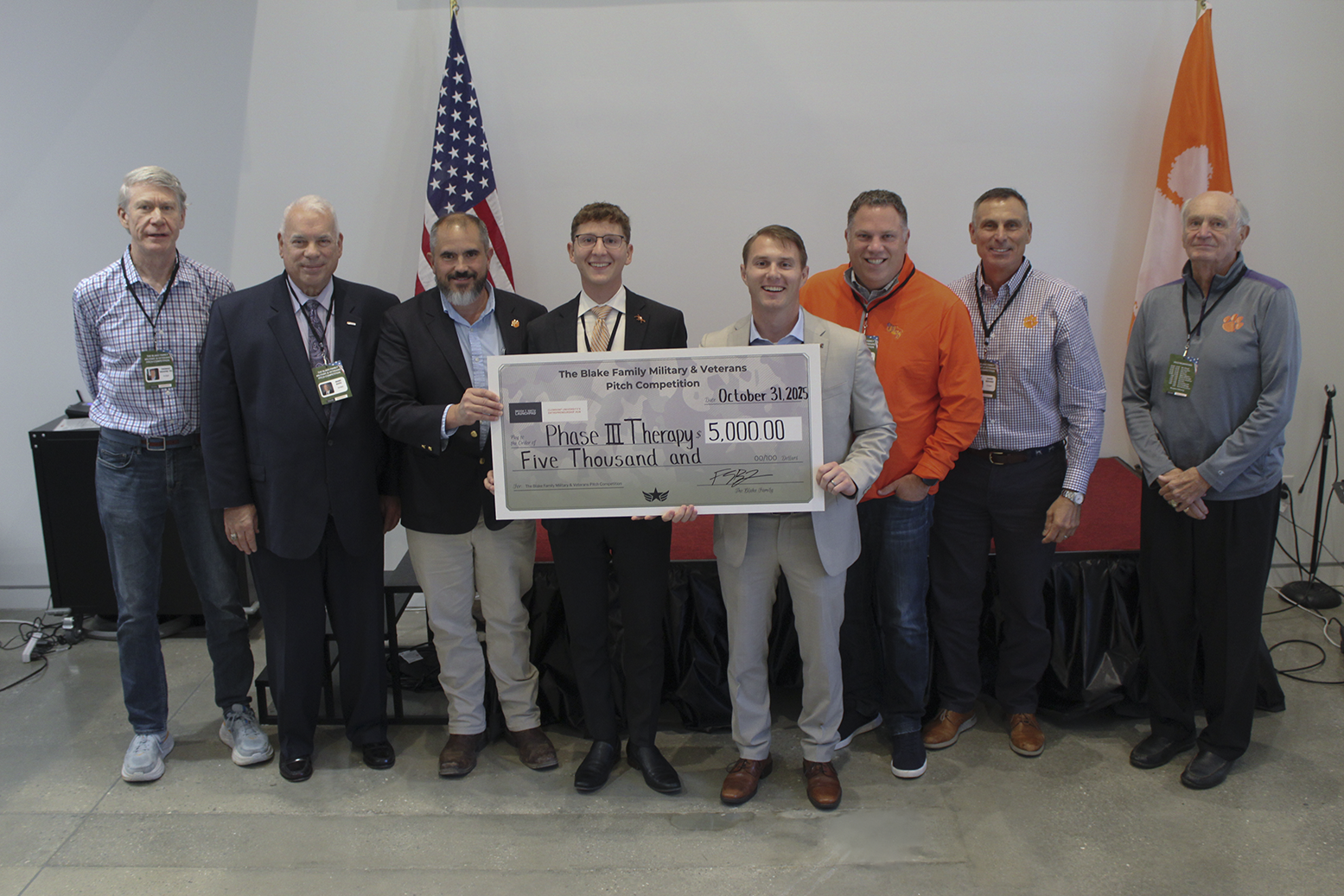 Group of eight individuals presenting a large check for $5,000 to support Phase III Therapy at a donation event.