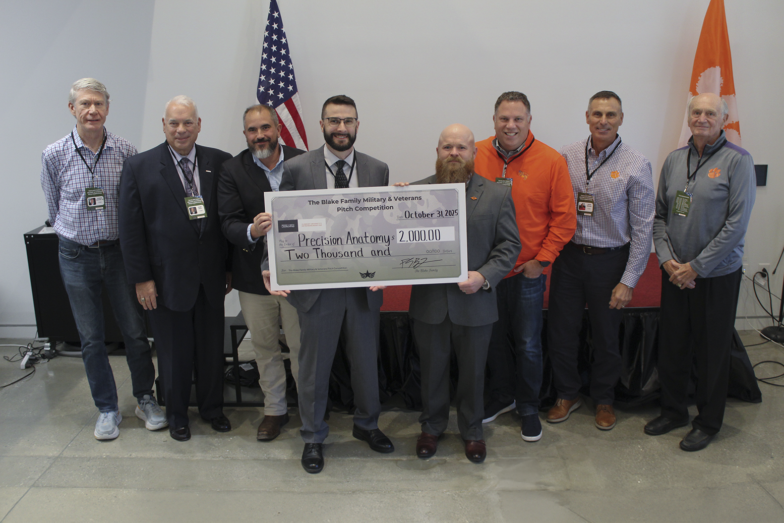 Group photo of award presenters and recipients holding a large check for $2,000 in recognition of Precision Anatomy at the Blake Family Military & Veterans Pitch Competition.