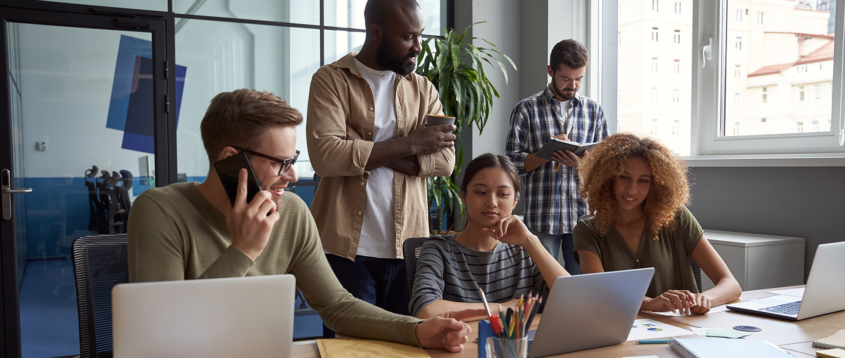 Group of professional working together in confernce room on laptop.