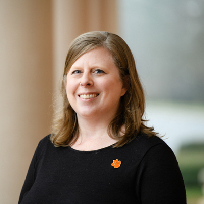 Photo of Kristy Pickurel wearing a dark colored top and a Clemson tiger paw pin.