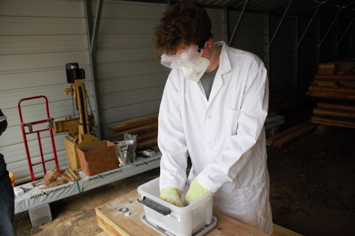 A CI student introduces a tool to lunar simulant to see the reaction
