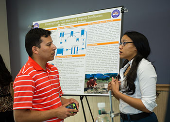 A graduate student mentor discusses a research poster with his student.
