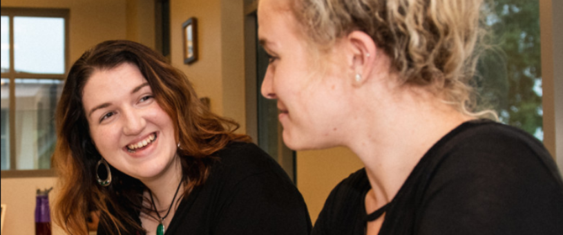 A writing consultant smiles at a graduate writer as they speak.