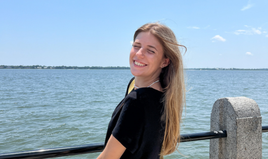 A blonde young woman leans into an ocean breeze.