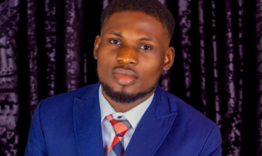 A young man in a blue suit with a blue and orange tie.