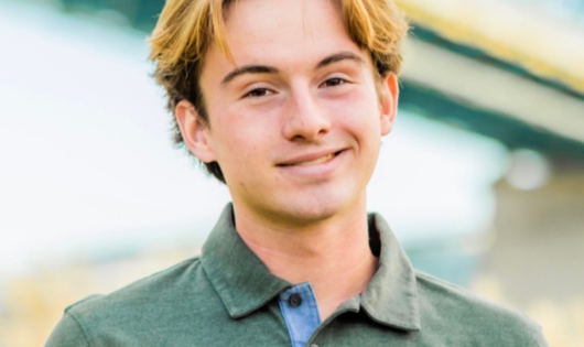 A blond young man smiles at the camera.