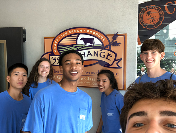 Six honors students wearing blue shirts smile for a selfie at the ’55 Exchange