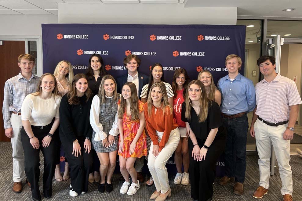 Several students standing together in front of an Honors College backdrop display.
