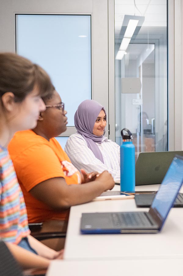 A female student sitting at a desk and working on a laptop.