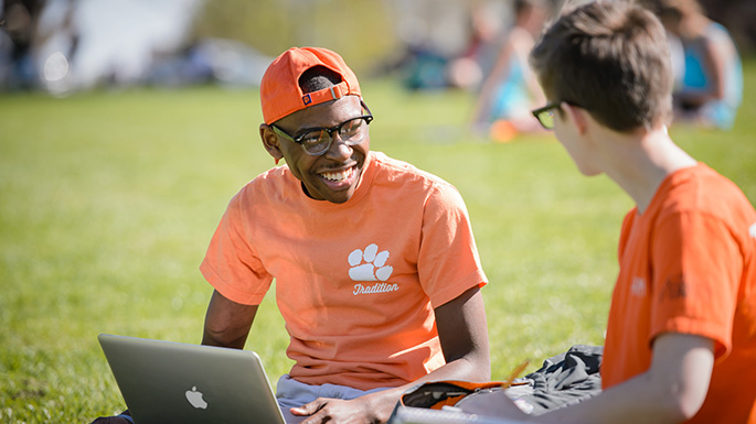 Students sitting and talking on Bowman field. 