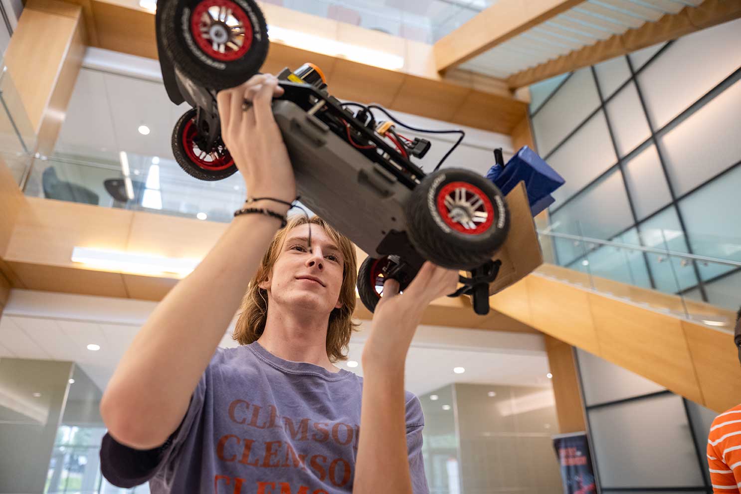 Grady Chapman standing in a lobby holding up and looking at an RC vehicle.