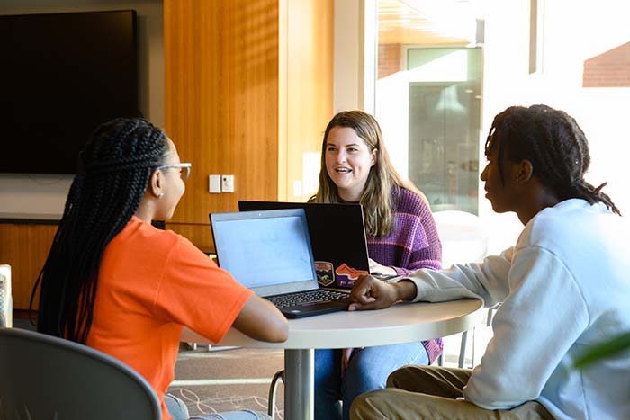 Three students work together at a table in the Honors Center