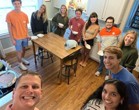 Students standing around a kitchen table as Dr. Pyle takes a selfie