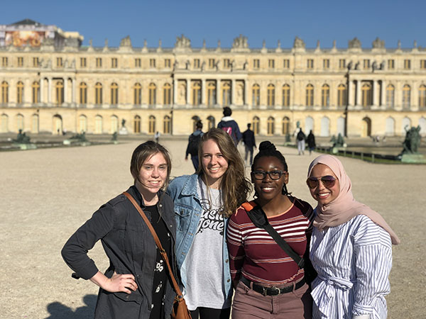 Four students posing together in front of the Versailles Palace