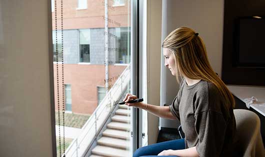 A student writing on a window in an Honors study room