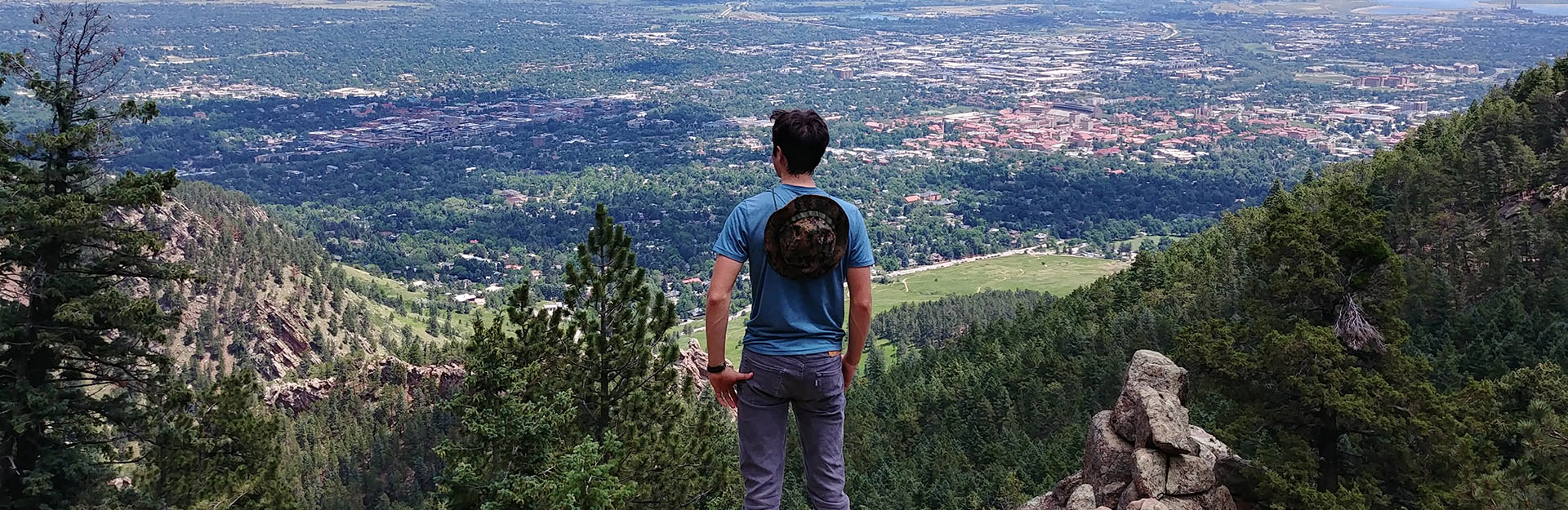 Back of student studying the horizon from a cliff