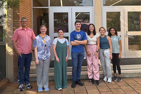 A group of students standing with a Clemson faculty member outside of a building on Clemson University campus. 