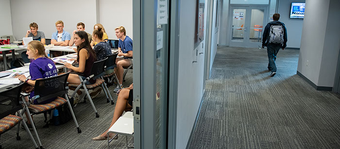 Split view of students in a classroom and a student walking down the Honors Center hallway