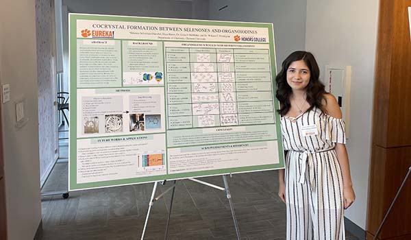 A Breakthrough Scholar posing next to a research poster she developed.