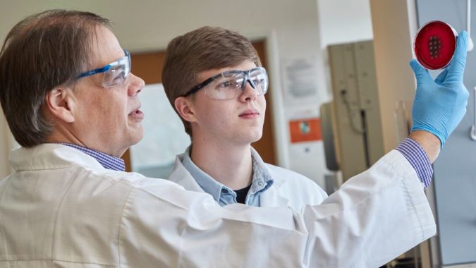 Kerry Smith inspects a petri dish with a student