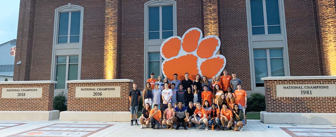 Students posing in front of the Clemson Athletics department on campus.