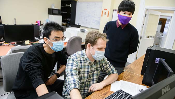Lao working at a computer with two students