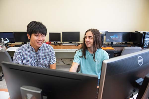 A EUREKA! faculty mentor and student smiling at laptop screens.