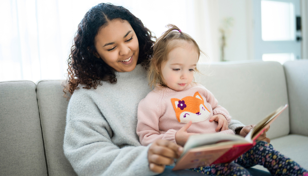 A teen babysitter reads to a young child.