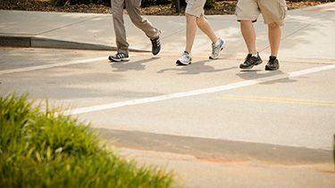 Three people crossing at a crosswalk.
