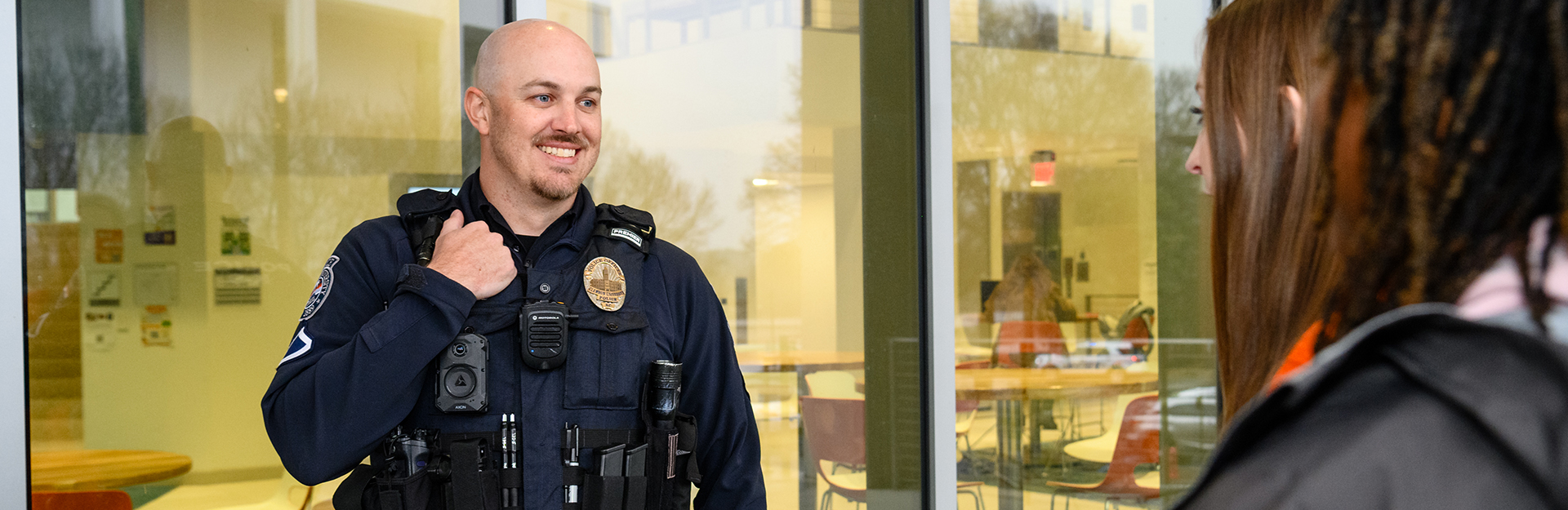 A police officer smiles while having a conversation with two students