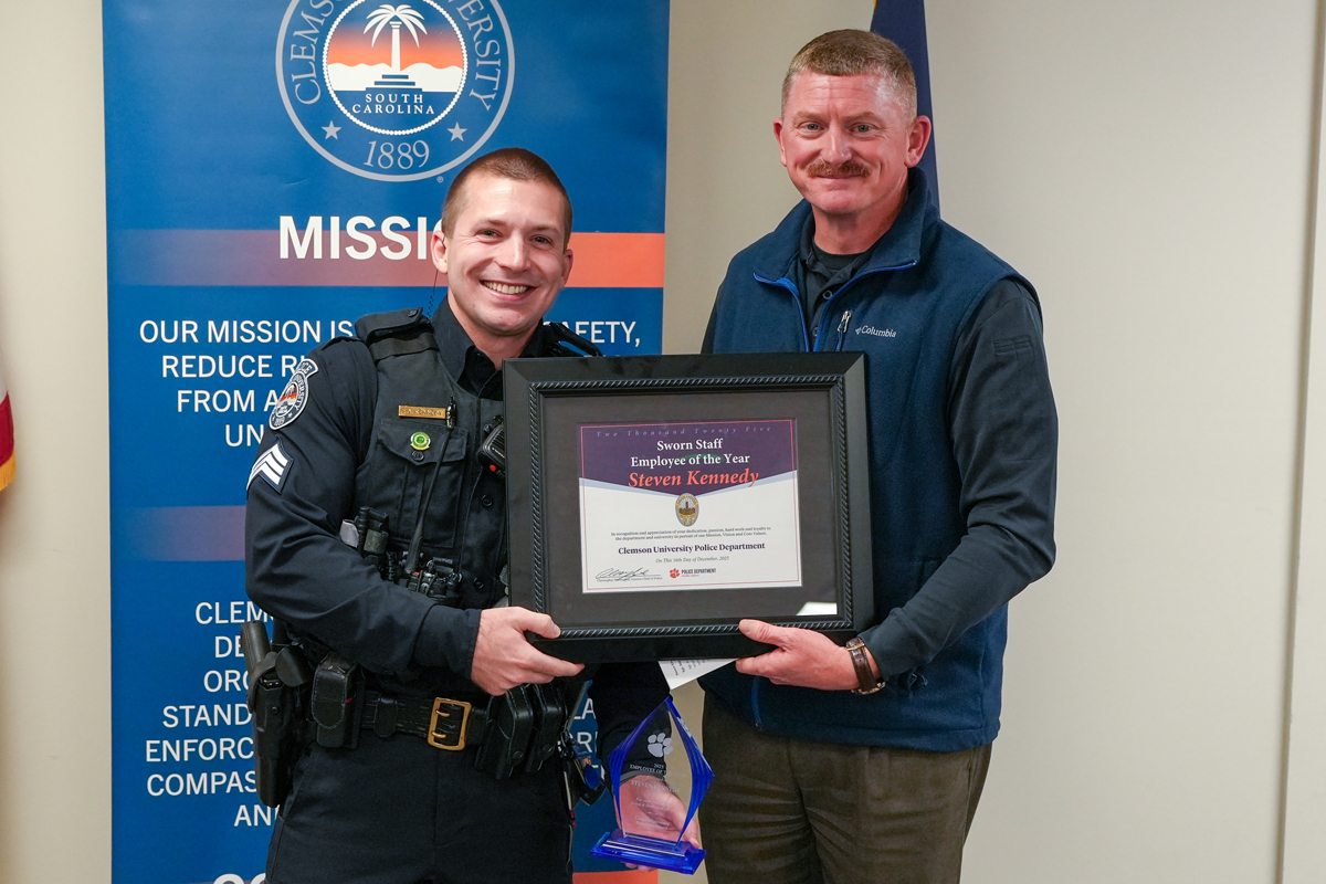 Two Clemson University staff members pose holding a framed “Sworn Staff Employee of the Year” award certificate.