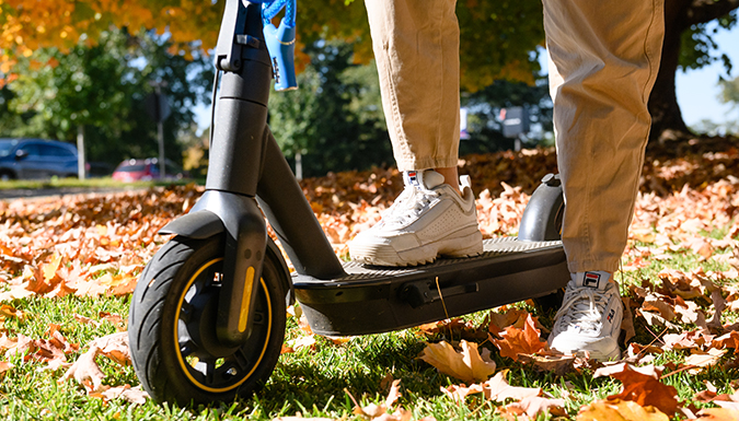 A young person standing beside an electric scooter