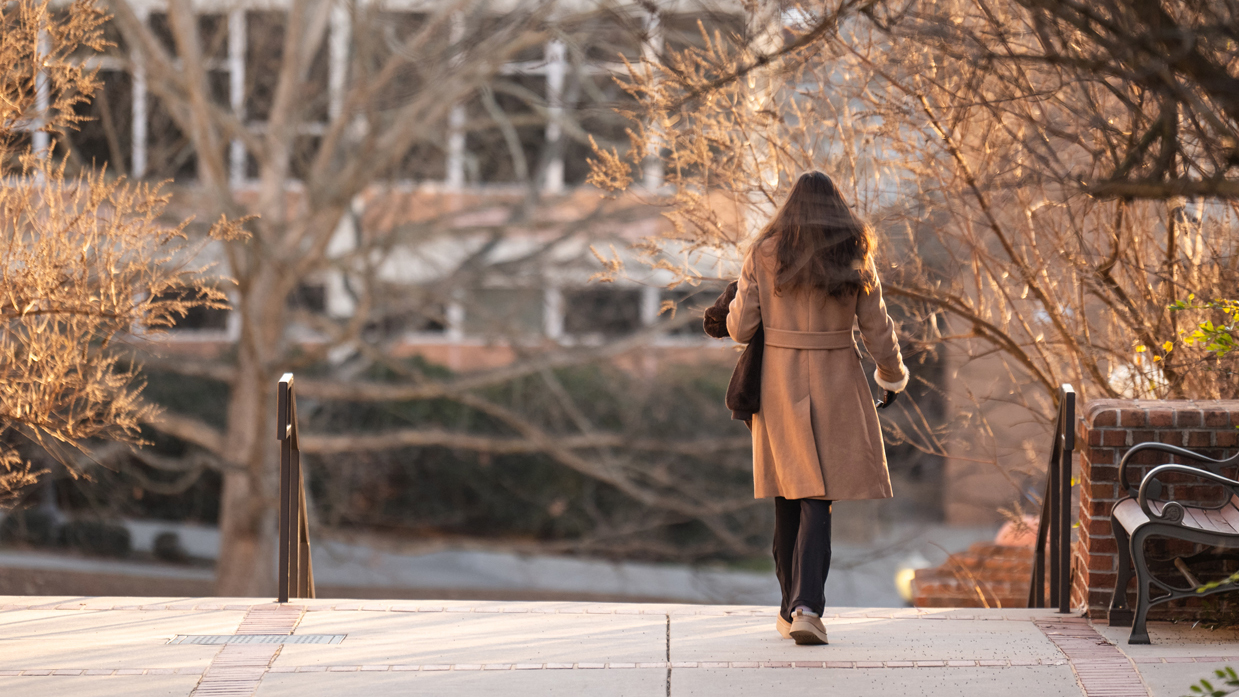 A female student walks on campus on a cold winter morning.