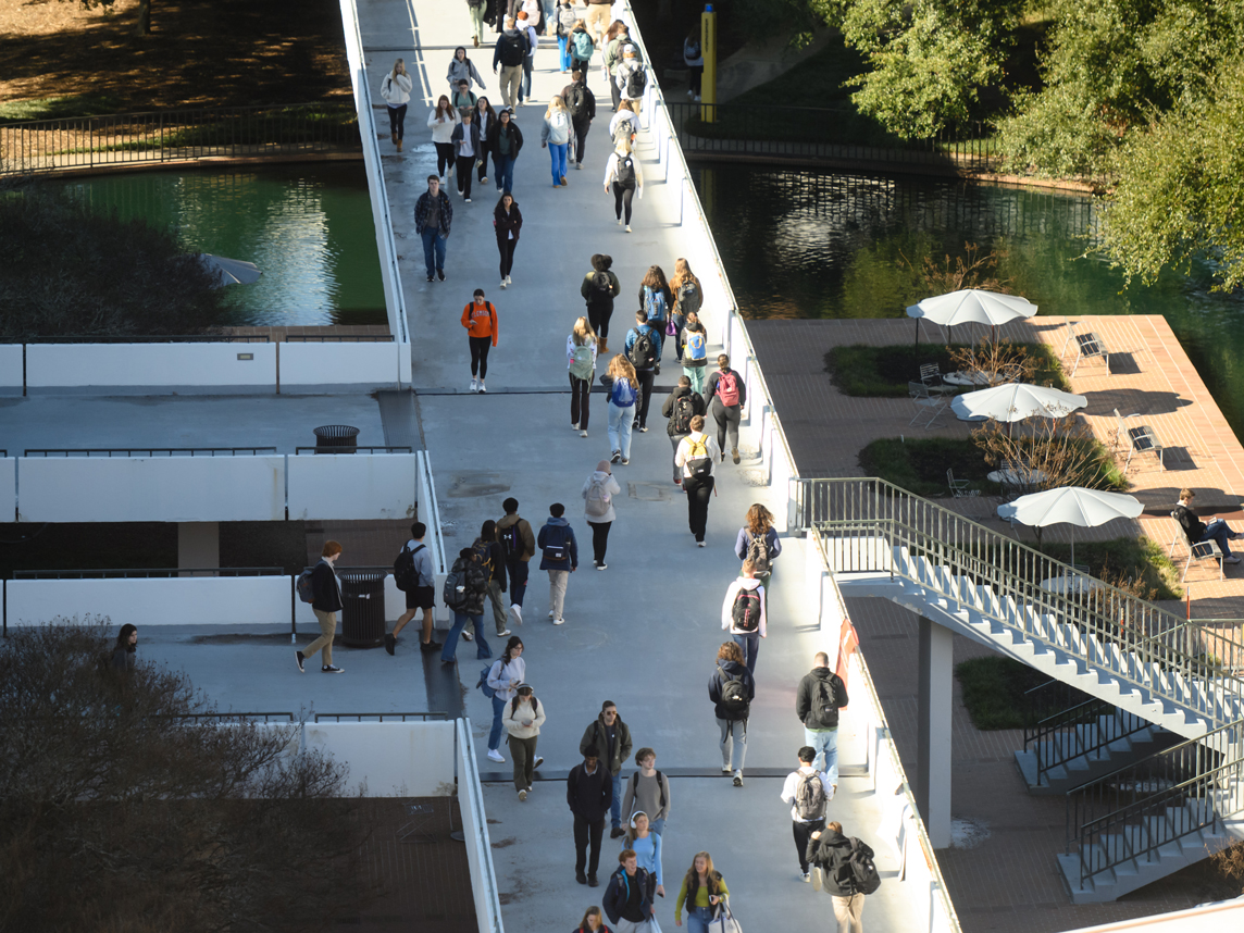 Students walk across the library bridge on a winter day.