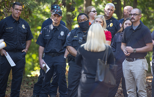 Group of EMS, Fire and Police listening to a woman speak to them. 